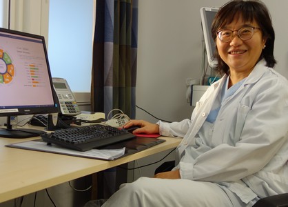 Forskaren Xioalei Hu sitter i en kontorsstol framför sitt skrivbord